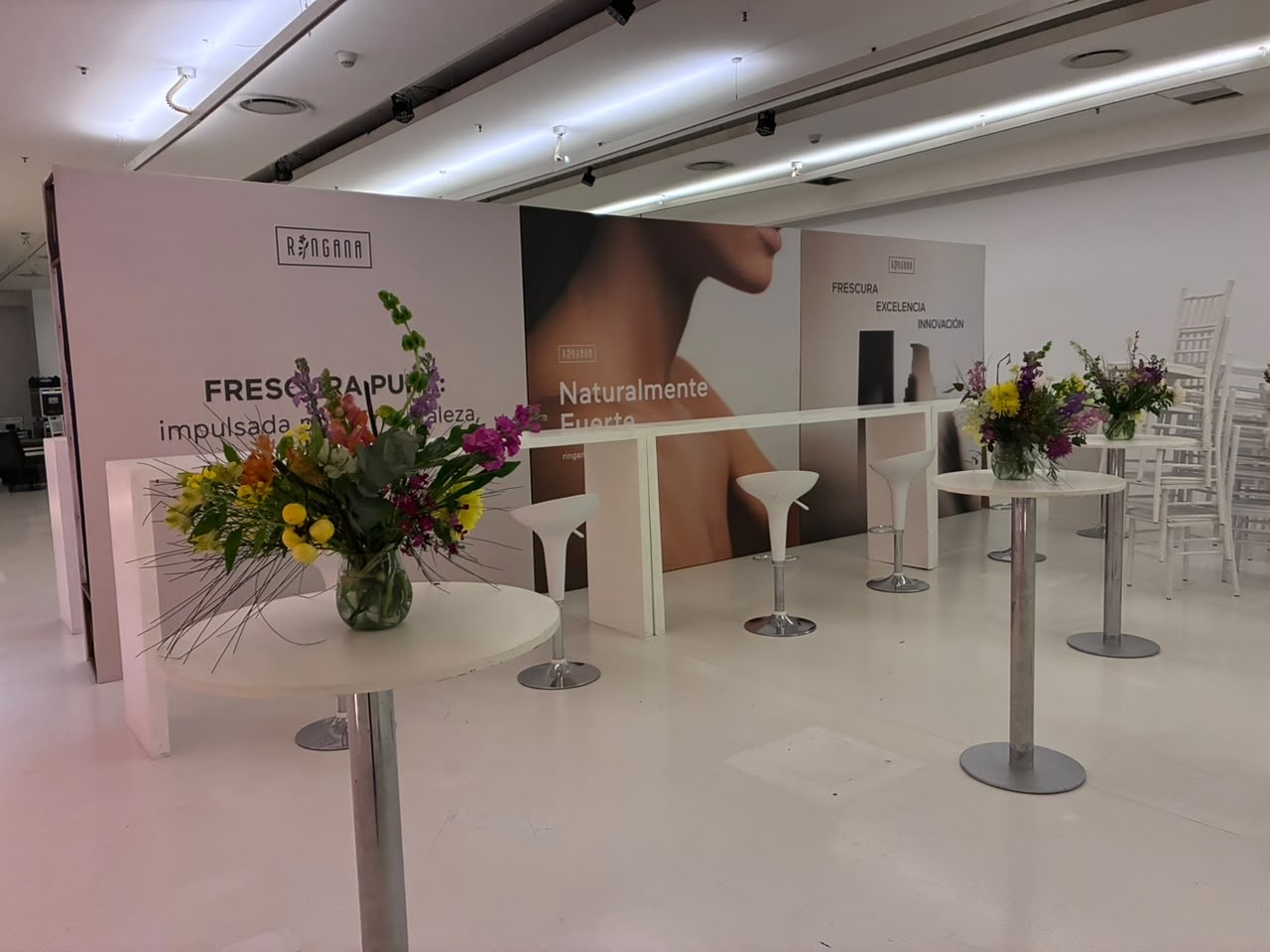 Stand RINGANA con ambientación de mesas altas y flores